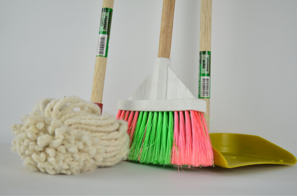 How to become a cleaner person: Picture of the bottoms of a mop, broom, and dustpan.