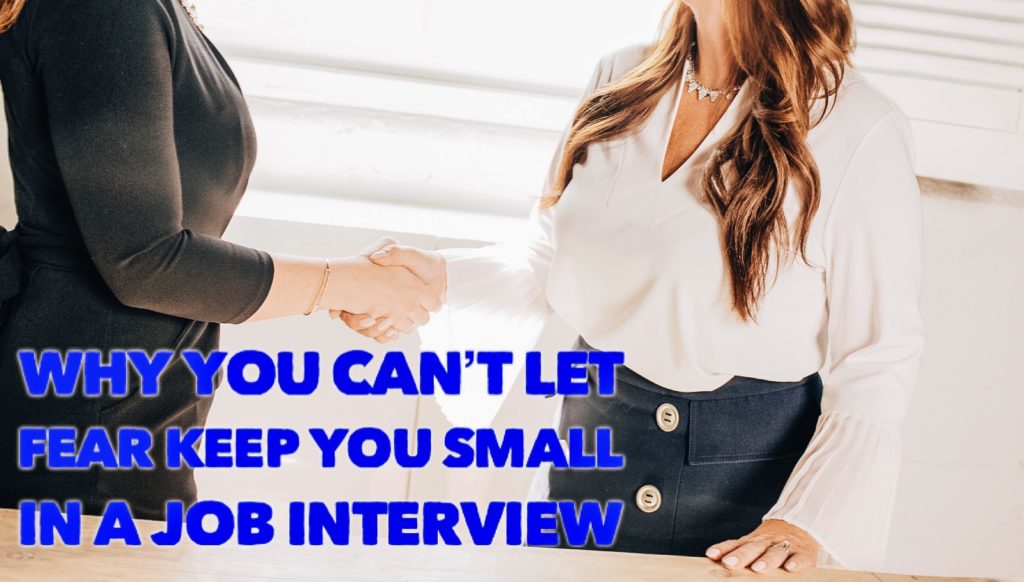 Two women shake hands with the text "Why You Can't Let Fear Keep You Small in a Job Interview" displayed over them.